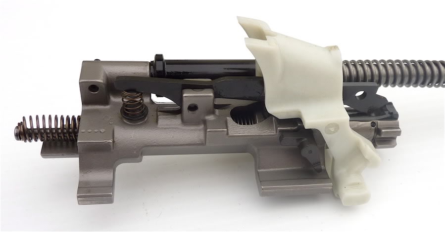 M�caniquement, le F2000 utilise une culasse rotative et un piston � course courte. La pi�ce en plastique est la bascule qui redirige les �tuis vers l'avant.