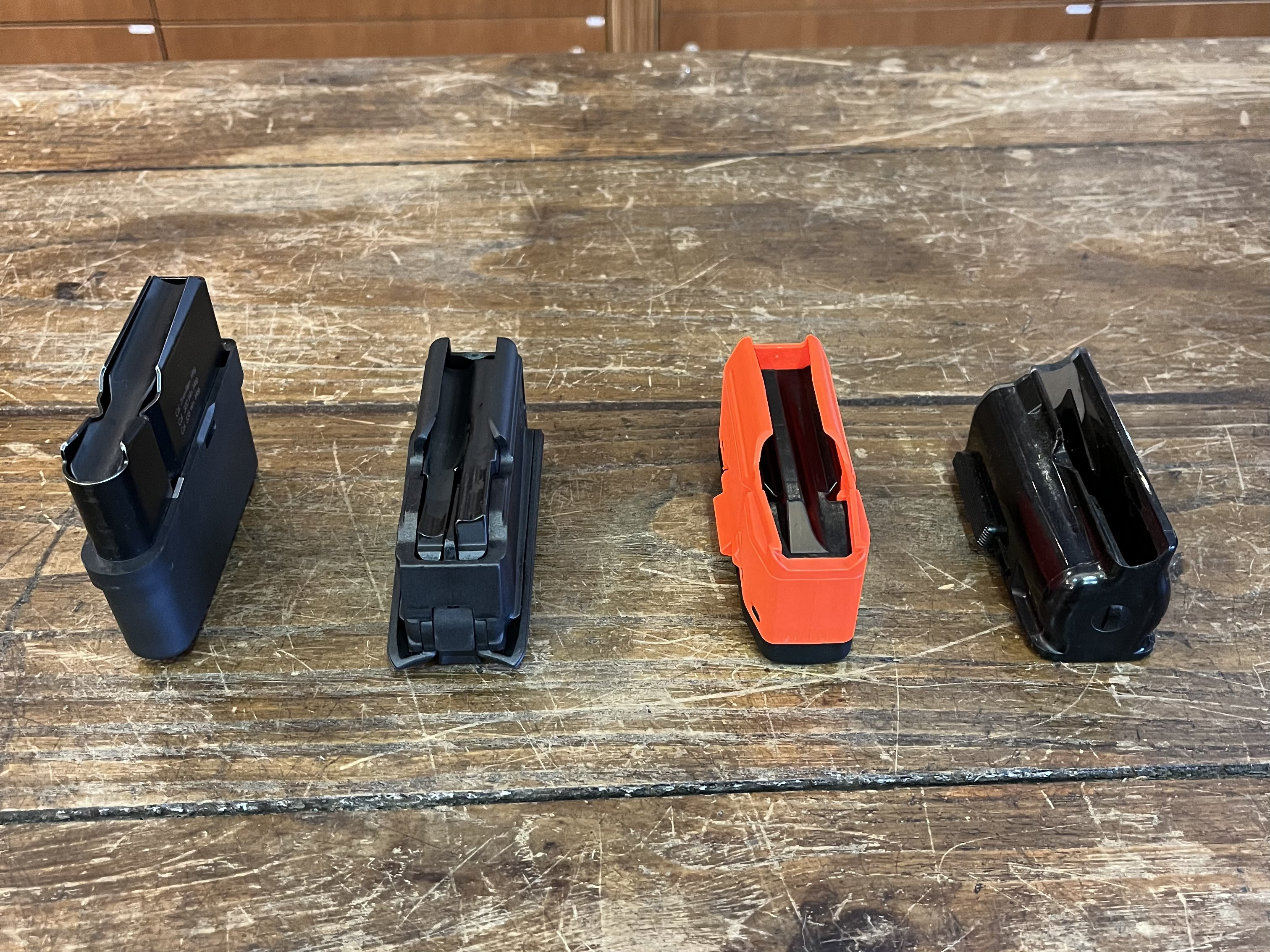 Quatre chargeurs : partant de la gauche, chargeur � simple pile grande capacit� ; chargeur � double pile imbriqu�e ; chargeur � double pile avec s�paration centrale ; chargeur rotatif, aussi appel� h�lico�dal.